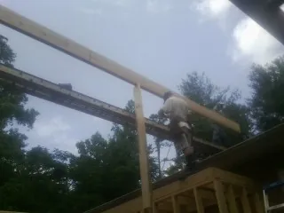 Carpenter setting a ridge beam over a new addition frame in South Holland
