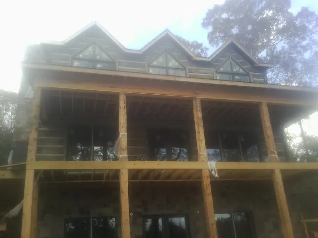 Dormers and porch framing on a large log home under construction — Roof Coating work by our crew in South Holland