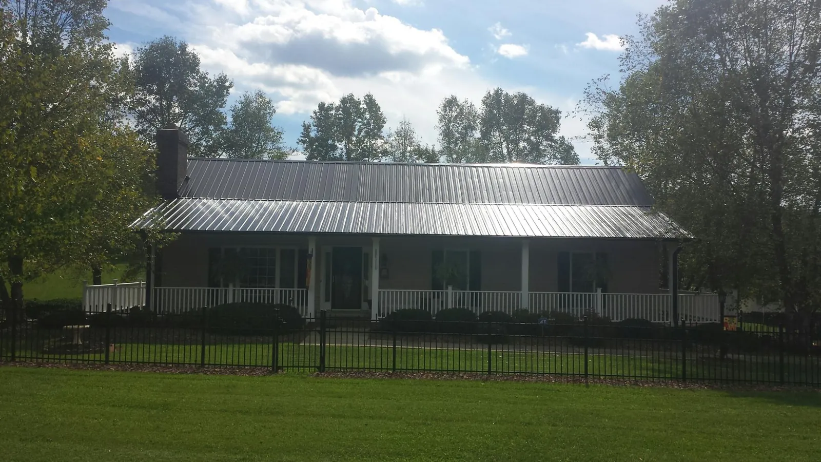 Gray metal roof on a brick ranch with a full width front porch — Gutter Guard Installation work by our crew in South Holland