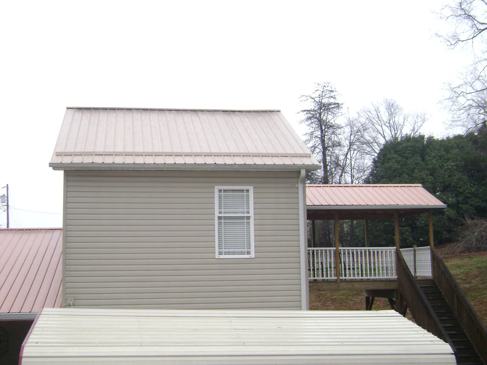 Tan metal roofs on a two story addition and attached porch, from a Roof Replacement job in South Holland