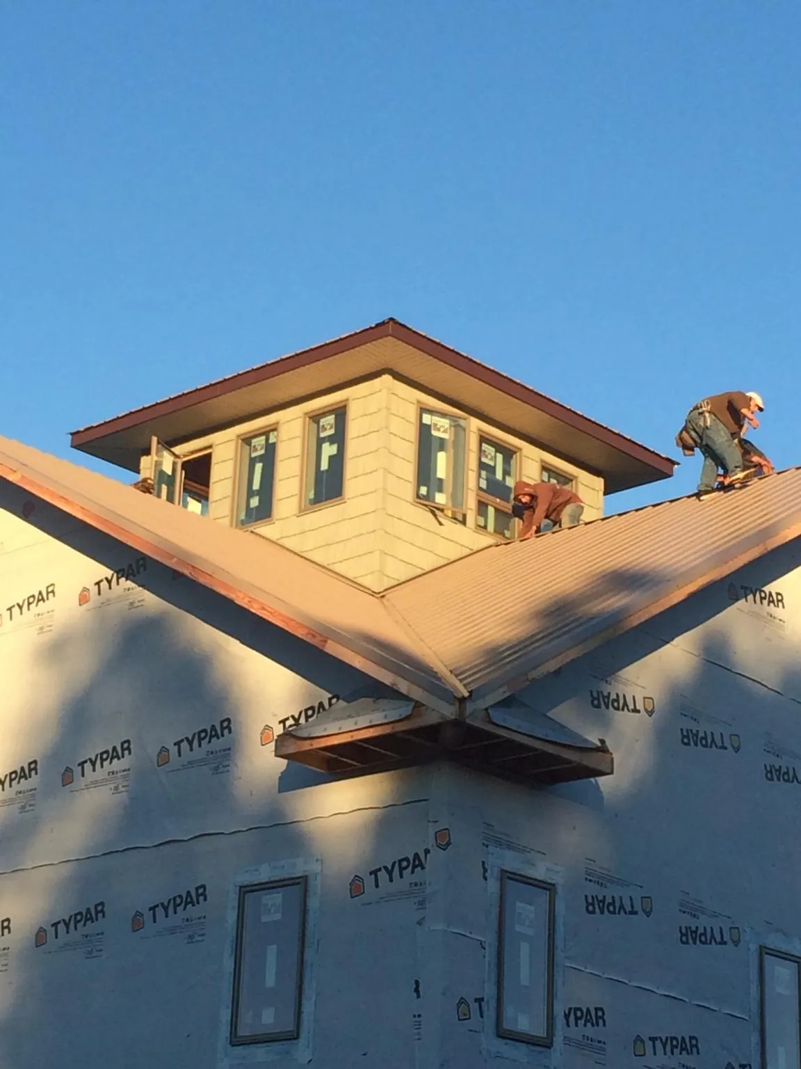 Roofers working around a rooftop cupola on a new metal roof at sunset — Roof Waterproofing in South Holland by Roofing Brothers